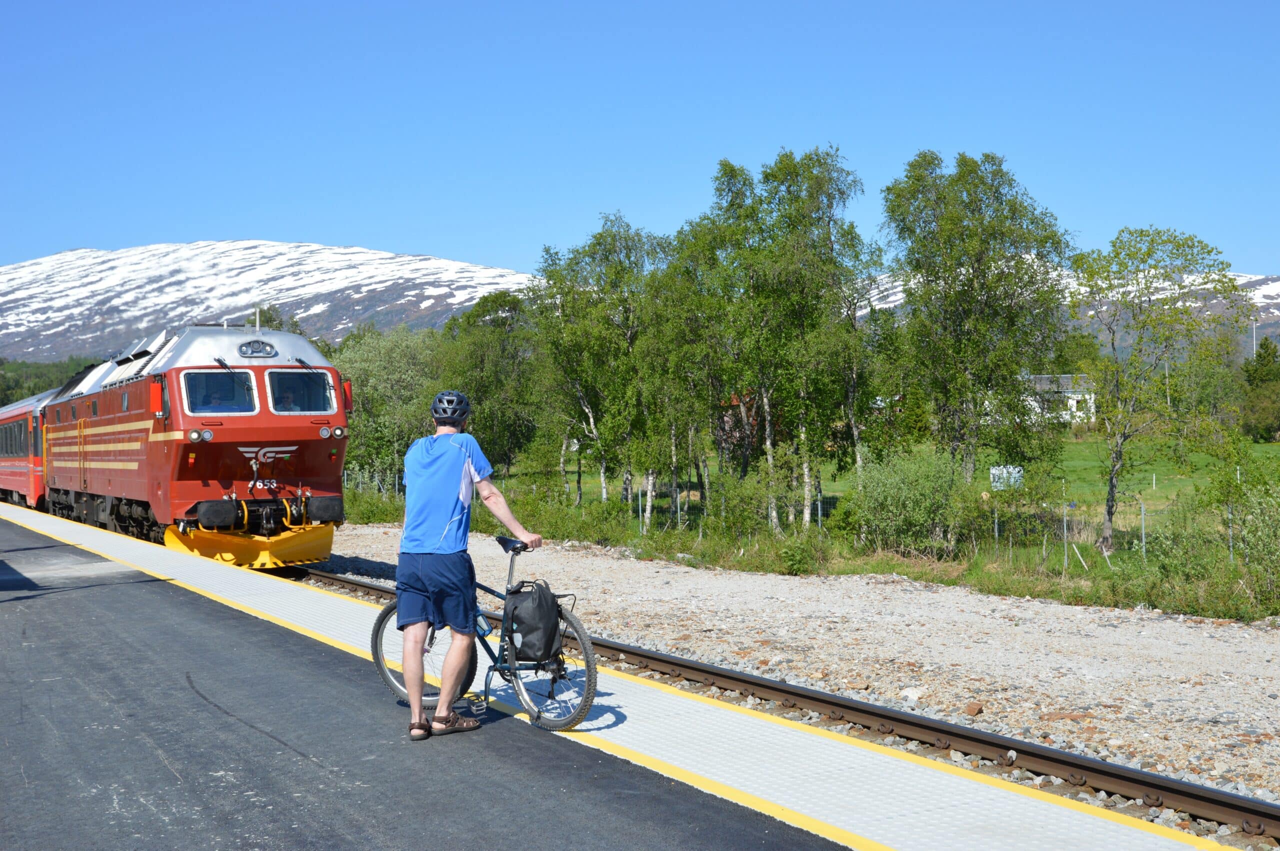 En mann med sykkel venter på regiontoget fra Bodø til Mo i Rana på Valnesfjord holdeplass